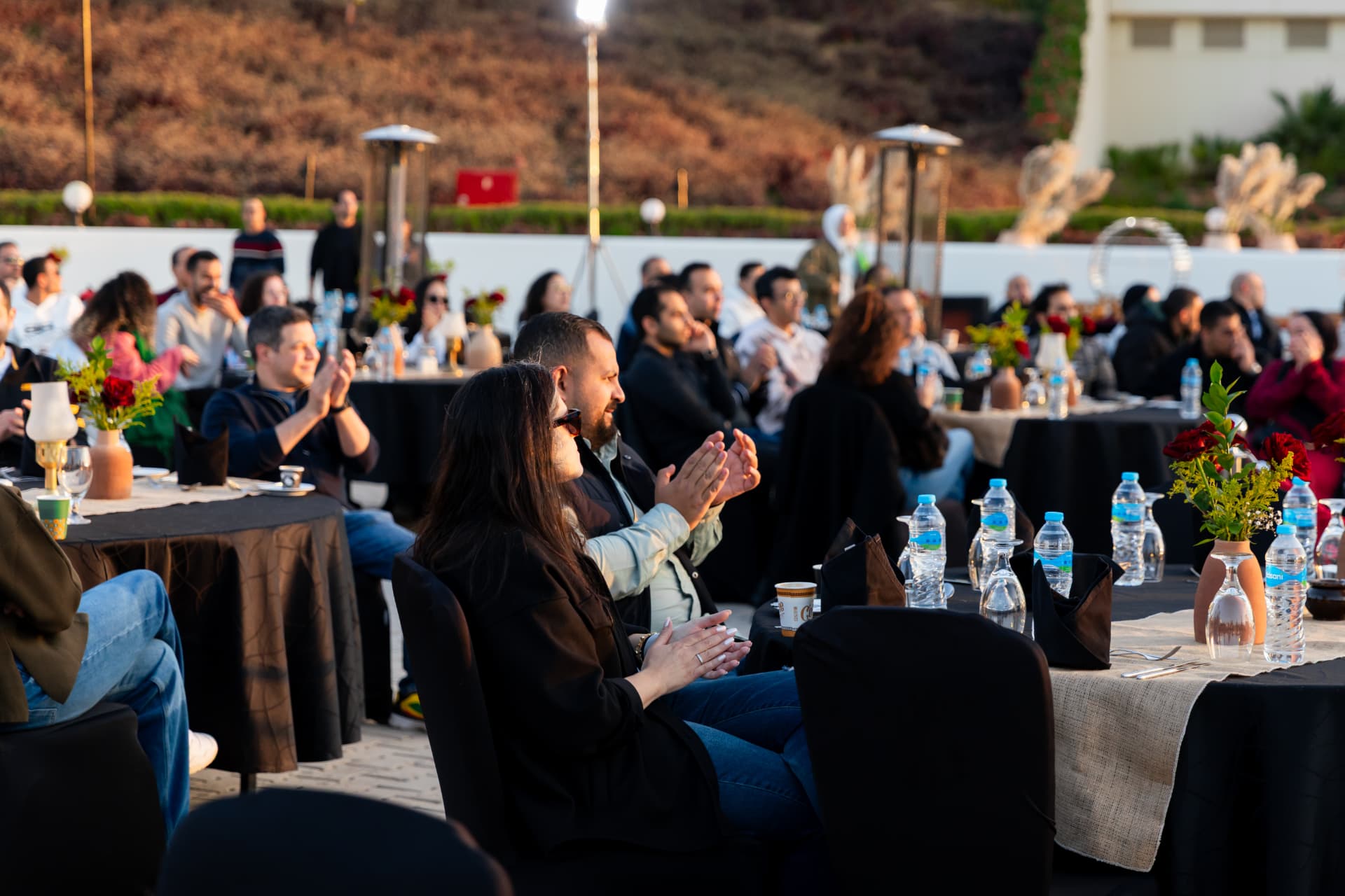 Corporate team seated around a desert camp fire circle at dusk