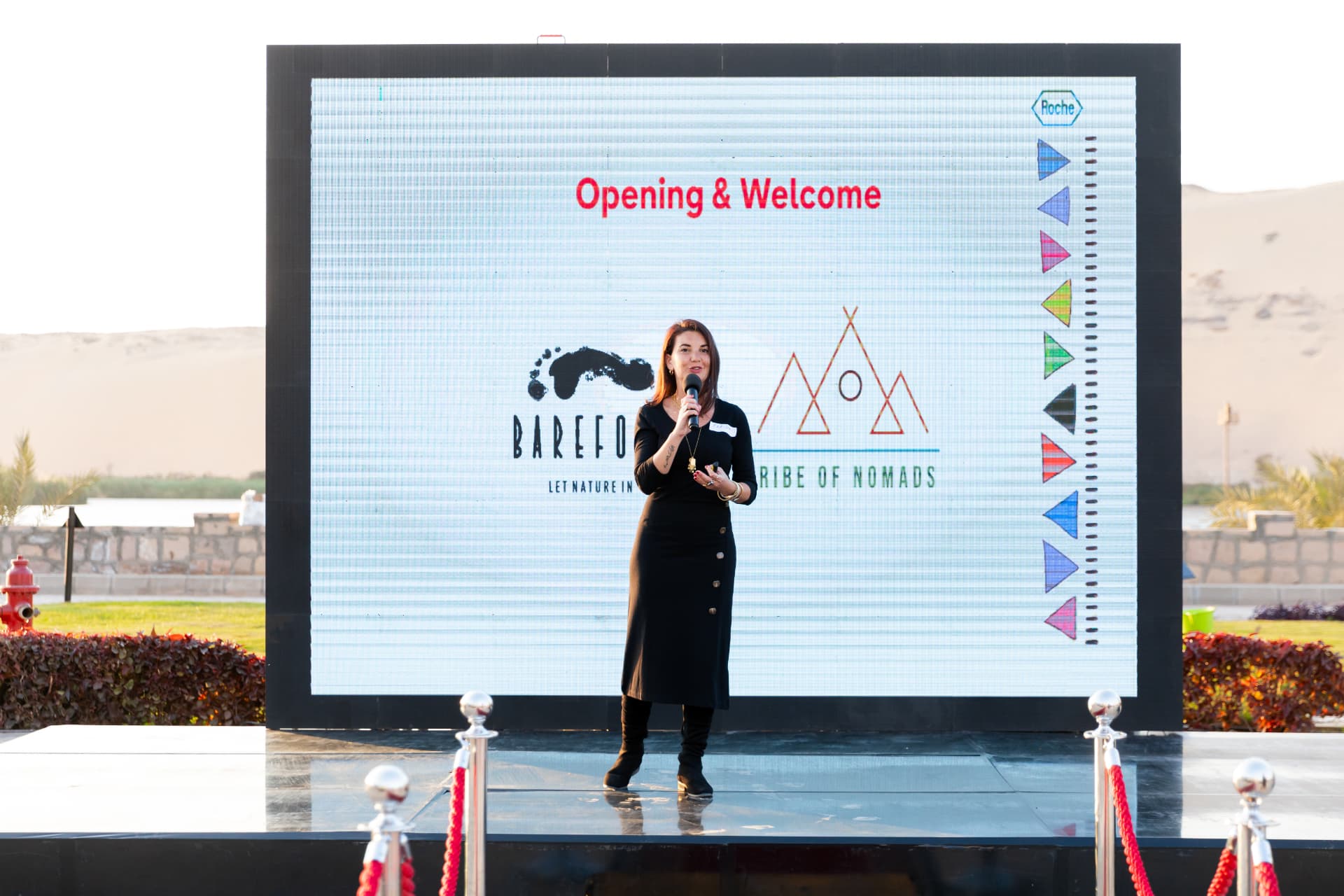 A speaker on stage during an opening keynote at an outdoor corporate event