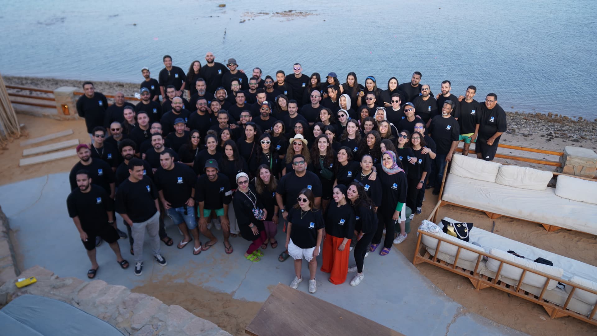 A large corporate group photo by the water at dusk