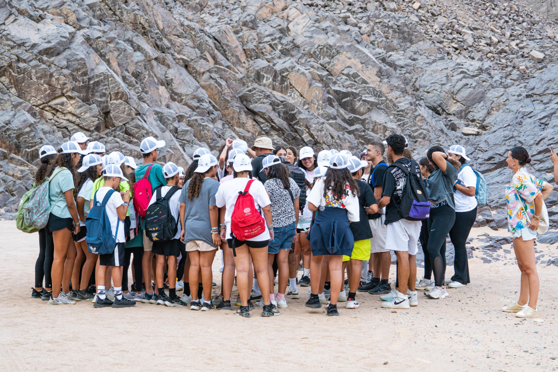 Youth group gathered for a briefing in a rocky desert wadi