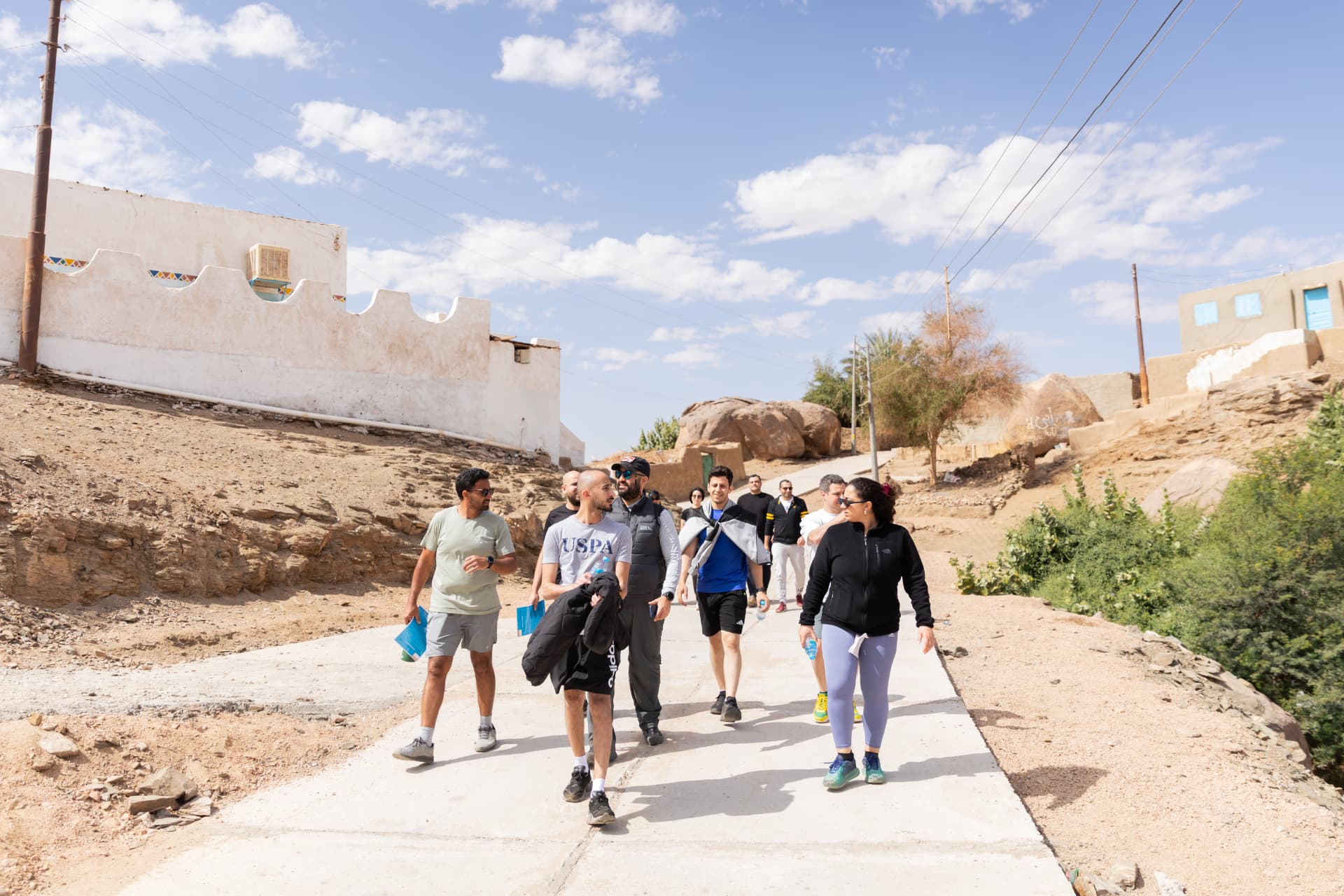 A corporate group walking through a scenic Nubian village path