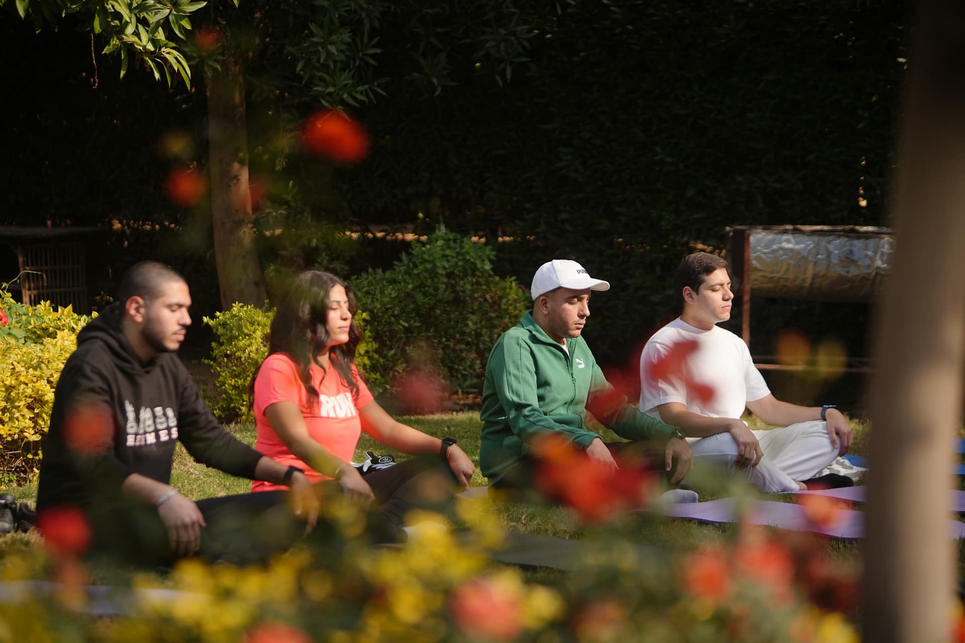 A group meditation and wellness session outdoors in a garden