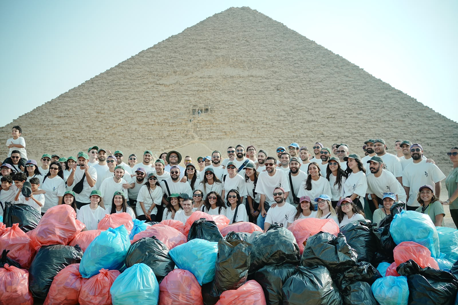 Volunteer team celebrating a cleanup campaign in front of the Giza Pyramids